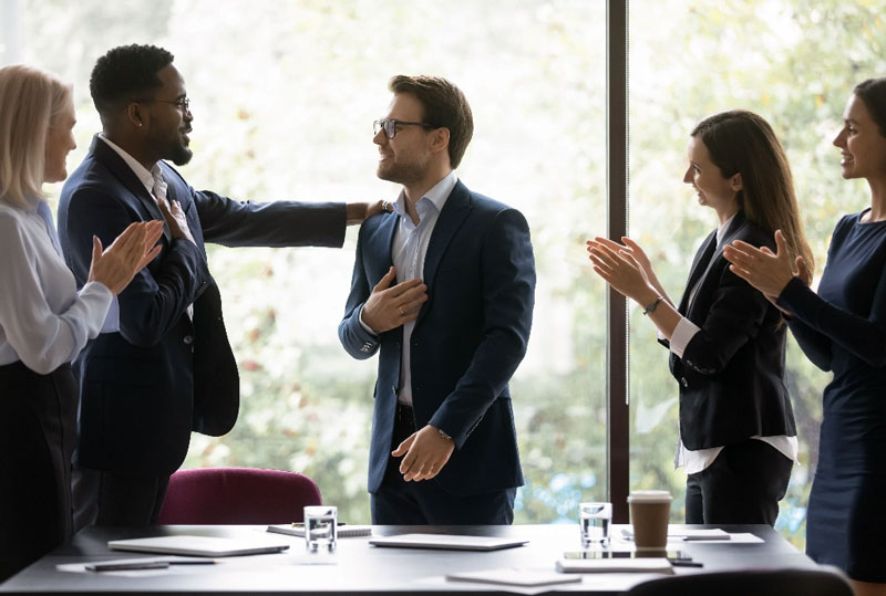 Five professionals with suites in a meeting congratulating each other