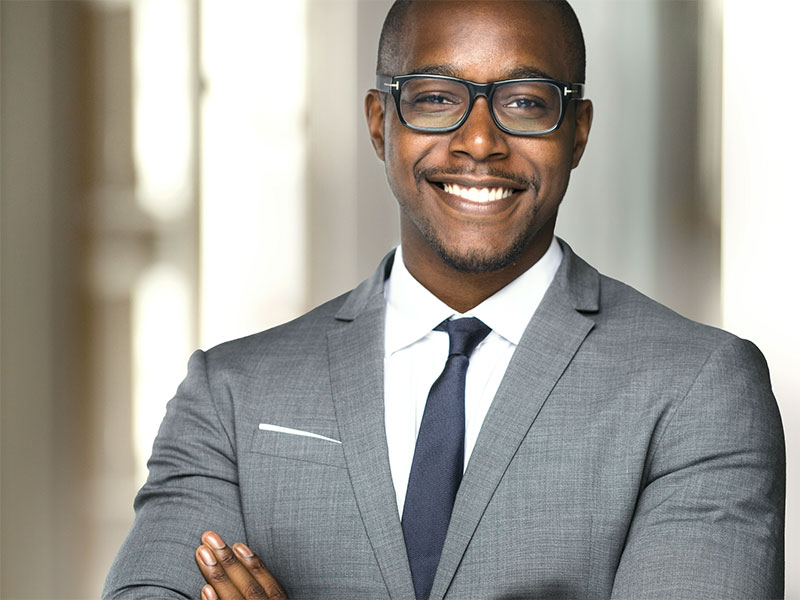 Professional with glasses and suit smiling.